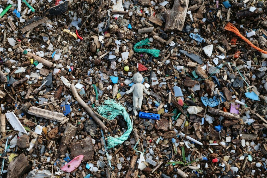 Plastic and wood debris scattered on a beach, highlighting pollution issues.