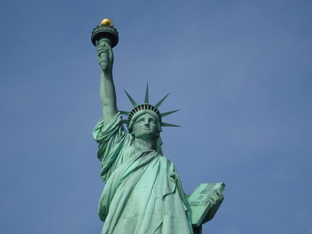 Iconic Statue of Liberty in New York with a vibrant blue sky backdrop, symbolizing freedom and hope.